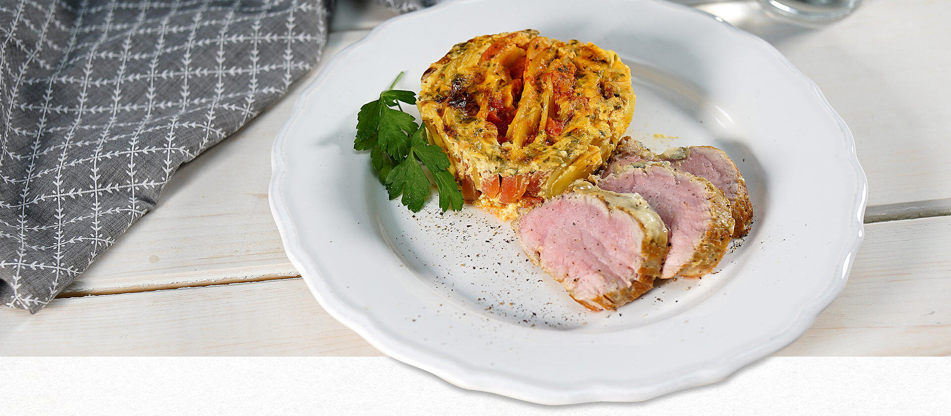Ein Teller mit gratiniertem Schweinefilet und Tomaten-Kartoffel-Gratin