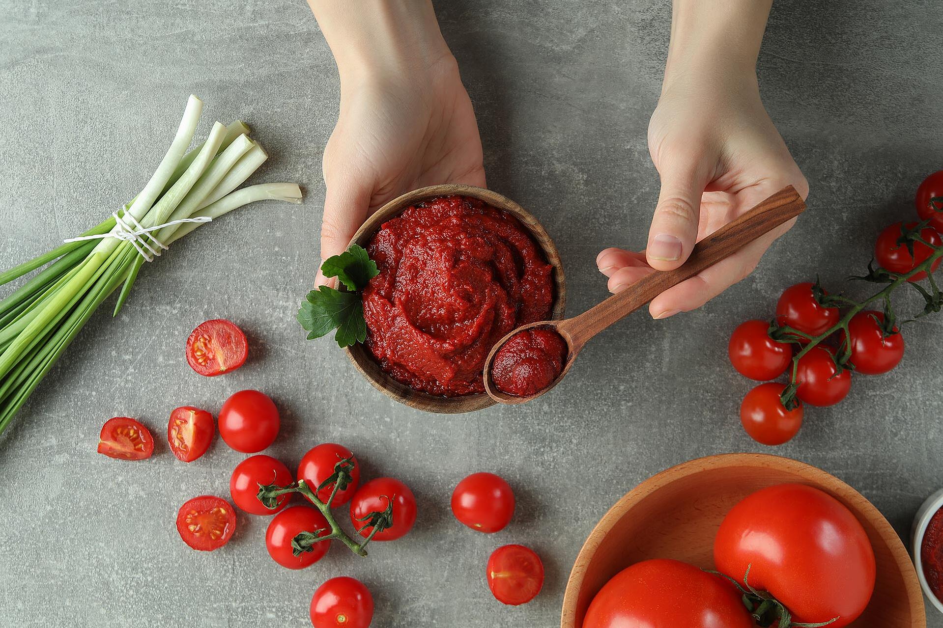 Tomatenmark in einer Holzschüssel und auf einem Holzlöffel