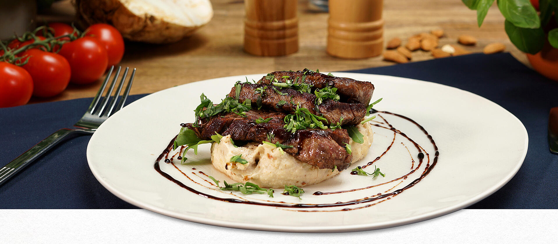 Ein Teller mit Sellerie-Pürree. Darauf wurden mehrere Scheiben Rinderfilet angerichtet und das Ganze mit Balsamico-Creme dekoriert