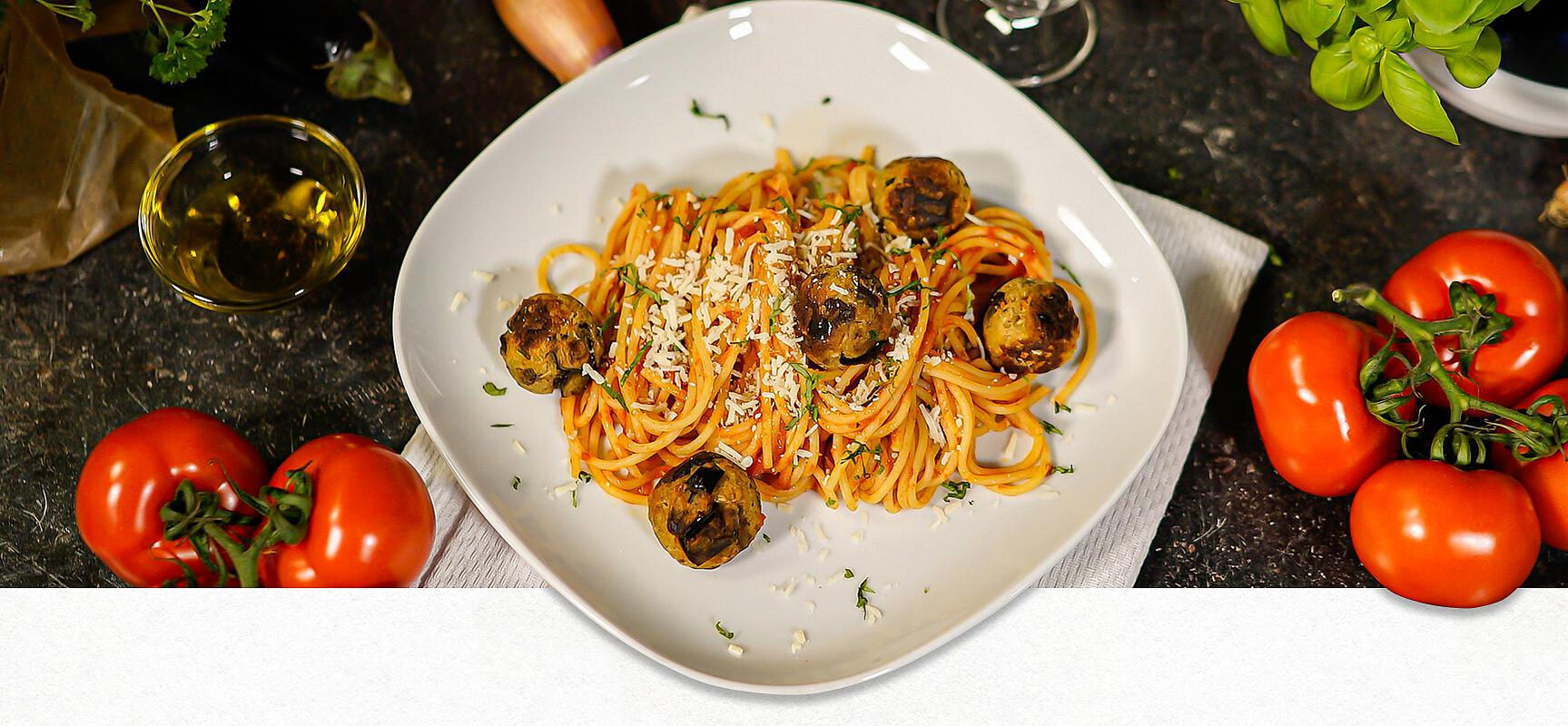 Ein weißer Teller, auf dem Spaghetti mit Auberginenbällchen platziert sind