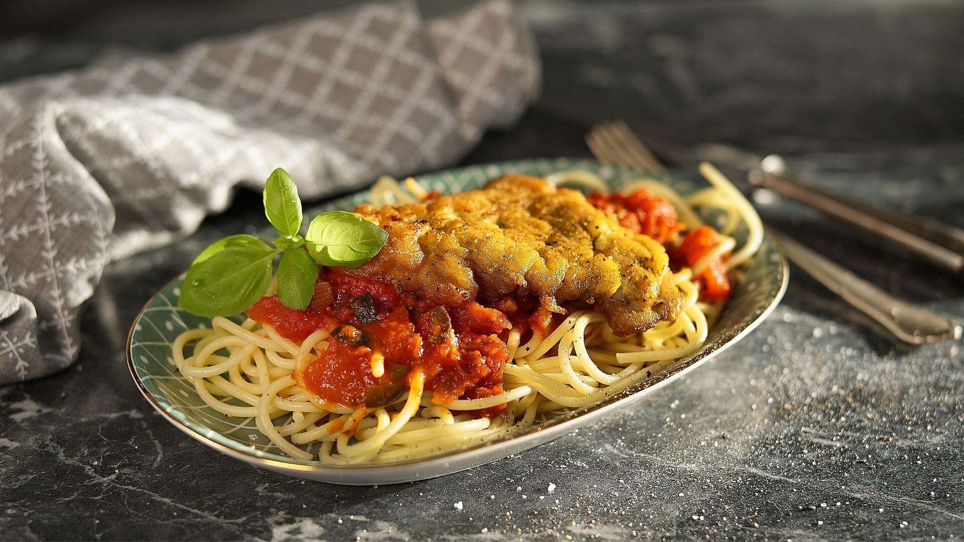 Ein Teller mit Pasta, Sauce und Schnitzel Mailänder Art
