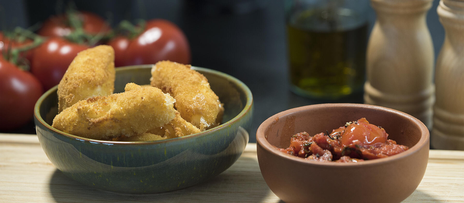 Mozzarella sticks in a green bowl and a smaller bowl with a dip next.