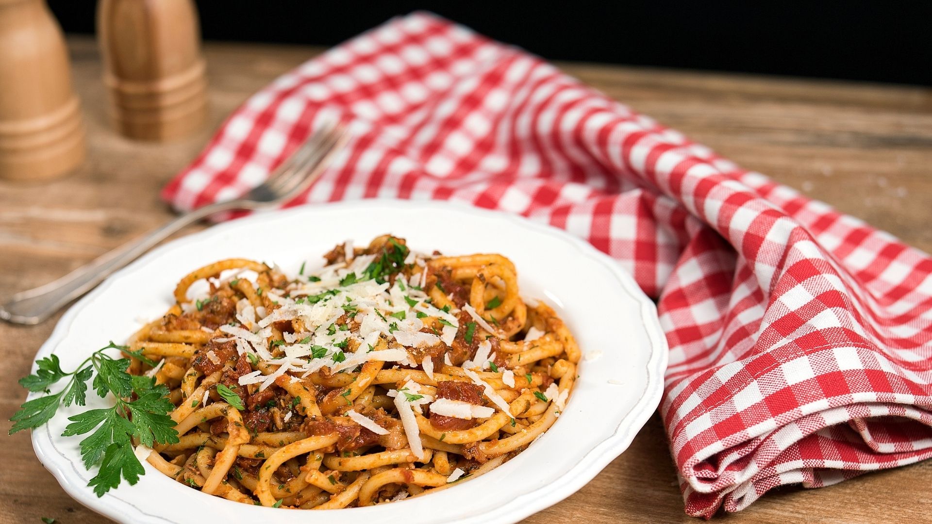 Bucatini-Nudeln mit Tomatensauce auf einem weißen Teller angerichtet. 