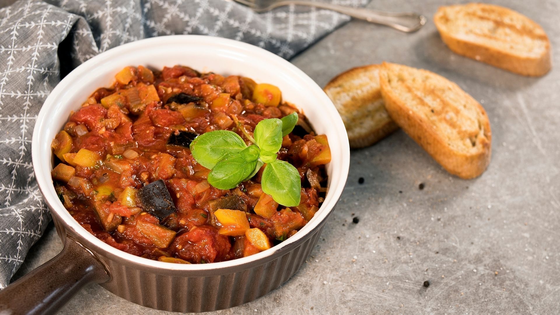 Eine Schüssel gefüllt mit dem italienischen Schmortopf Ciambotta, mit Basilikum garniert