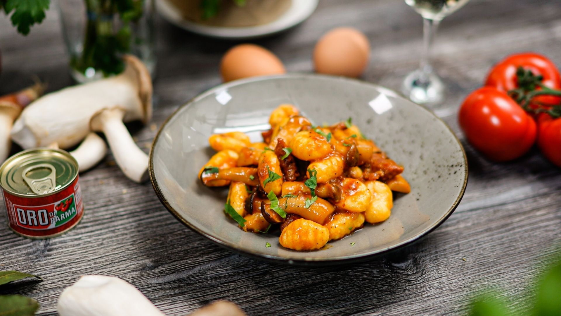 Gnocchi mit Pilzen und Salsiccia auf einem grauen Teller angerichtet