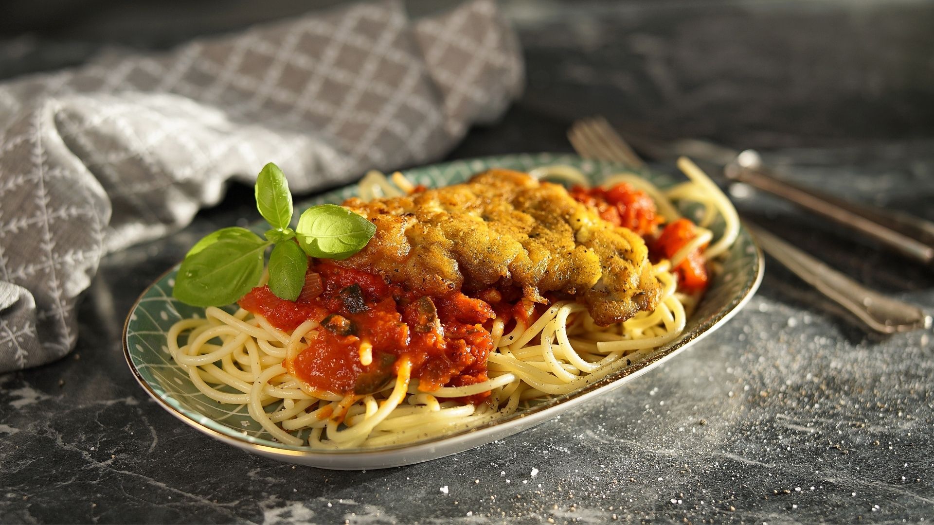Ein Teller mit Pasta, Sauce und Schnitzel Mailänder Art