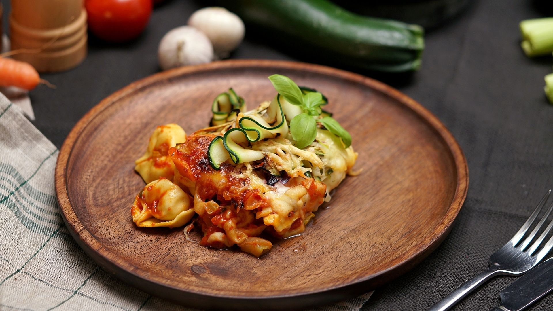 Ein Holzteller mit einer Portion Tortellini al forno