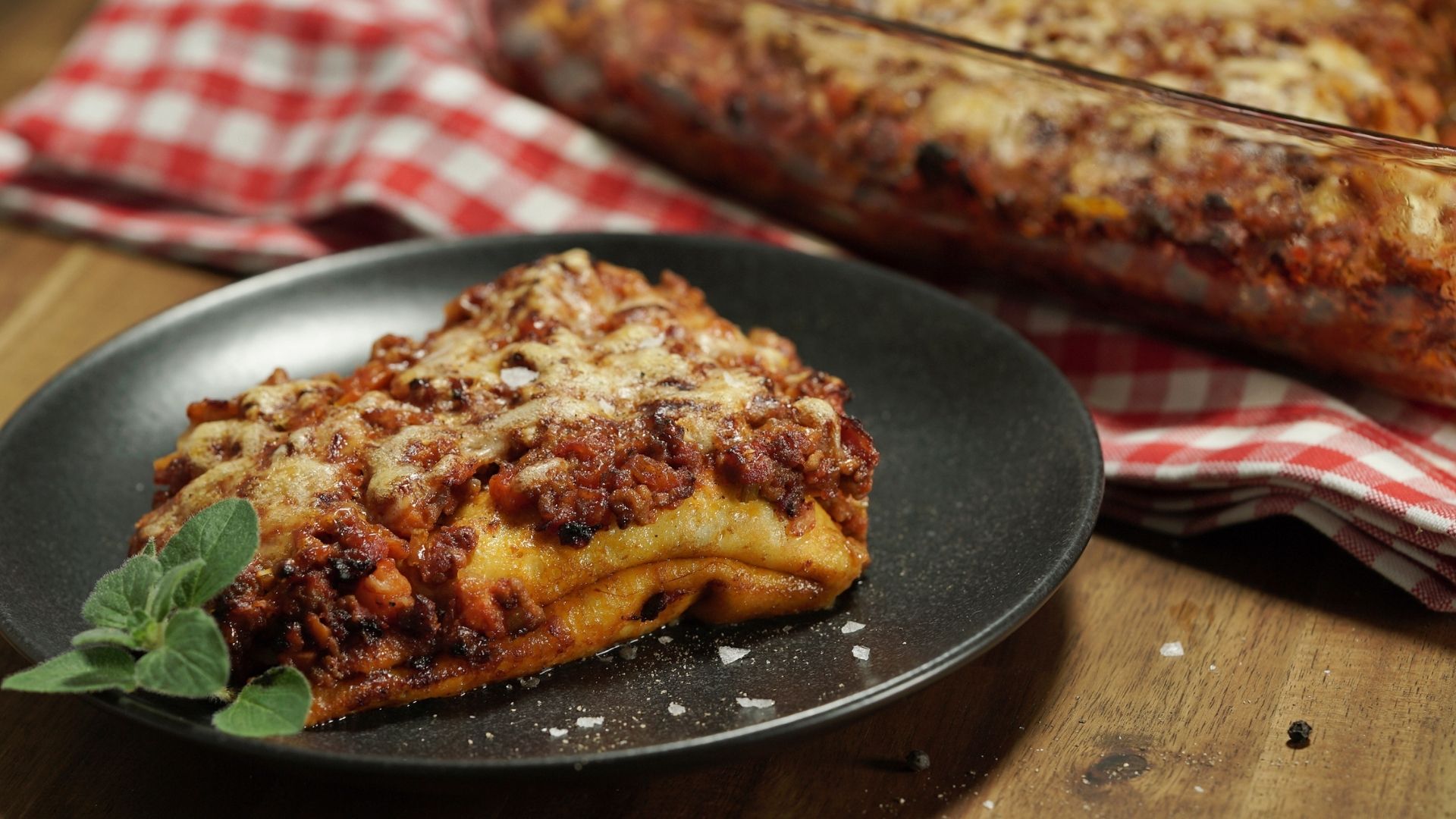Crespelle - italienische Pfannkuchen gefüllt mit Bolognese auf einem schwarzen Teller