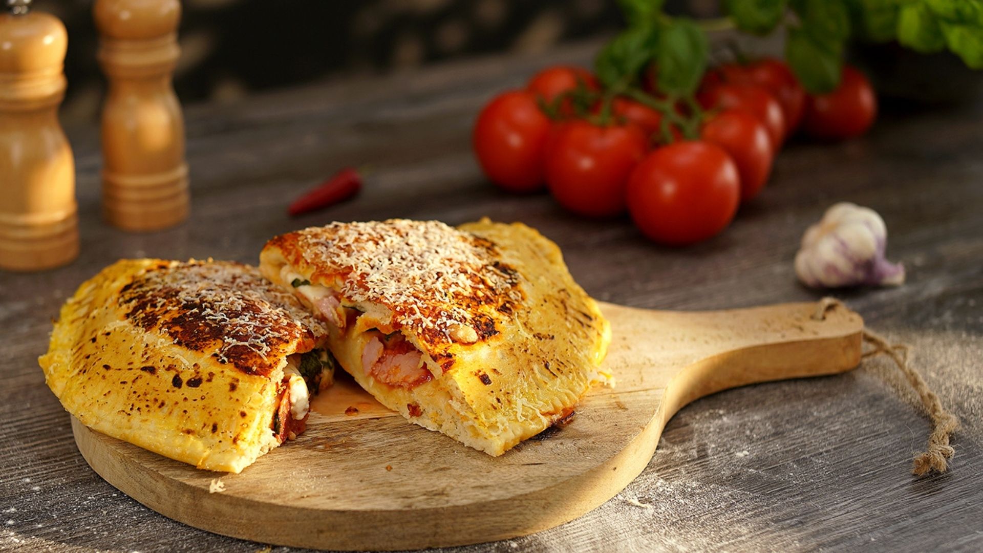 Ein rundes Holzbrett mit einer Calzone, die in der Hälfte zerteilt ist