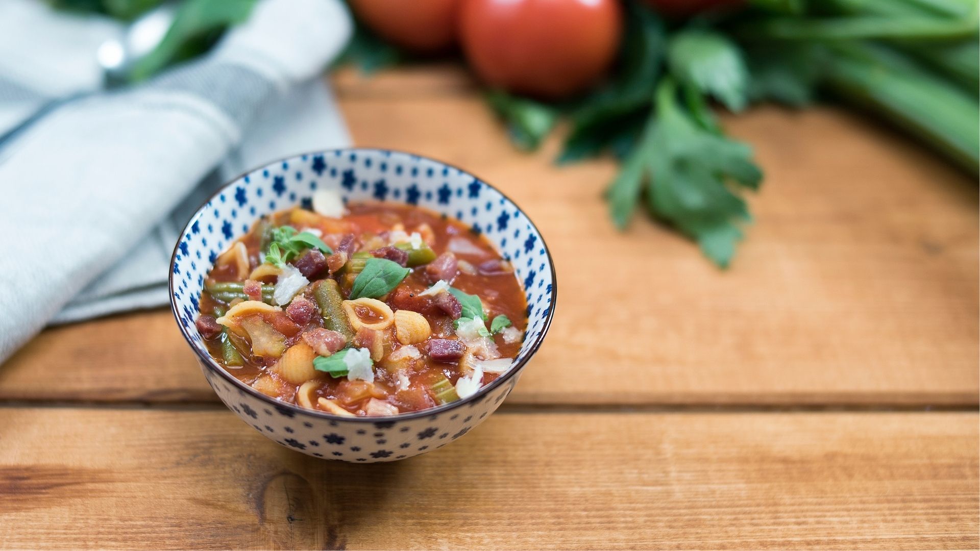 Minestrone in einer blau-weißen Schüssel mit Kräutern dekoriert