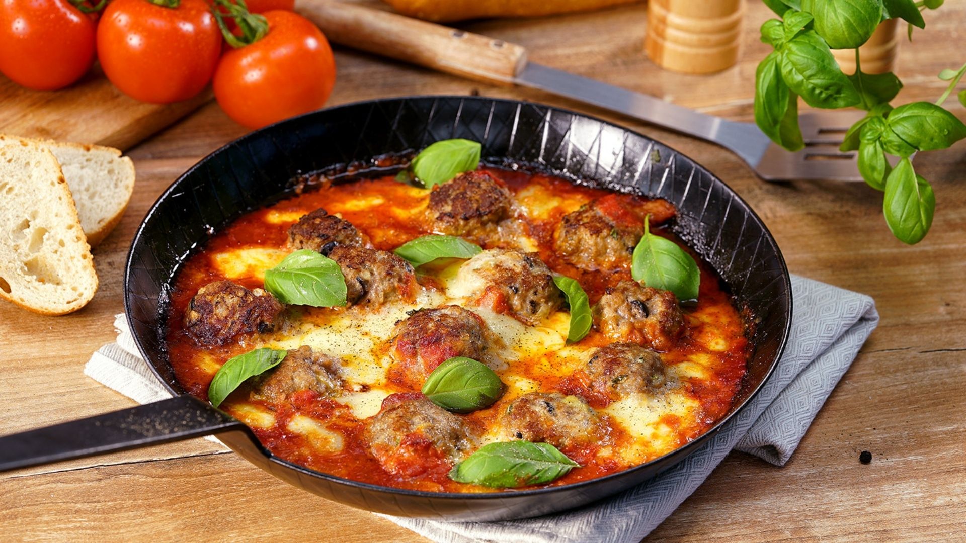 Überbackene Fleischbällchen in einer Pfanne, mit Basilikum garniert