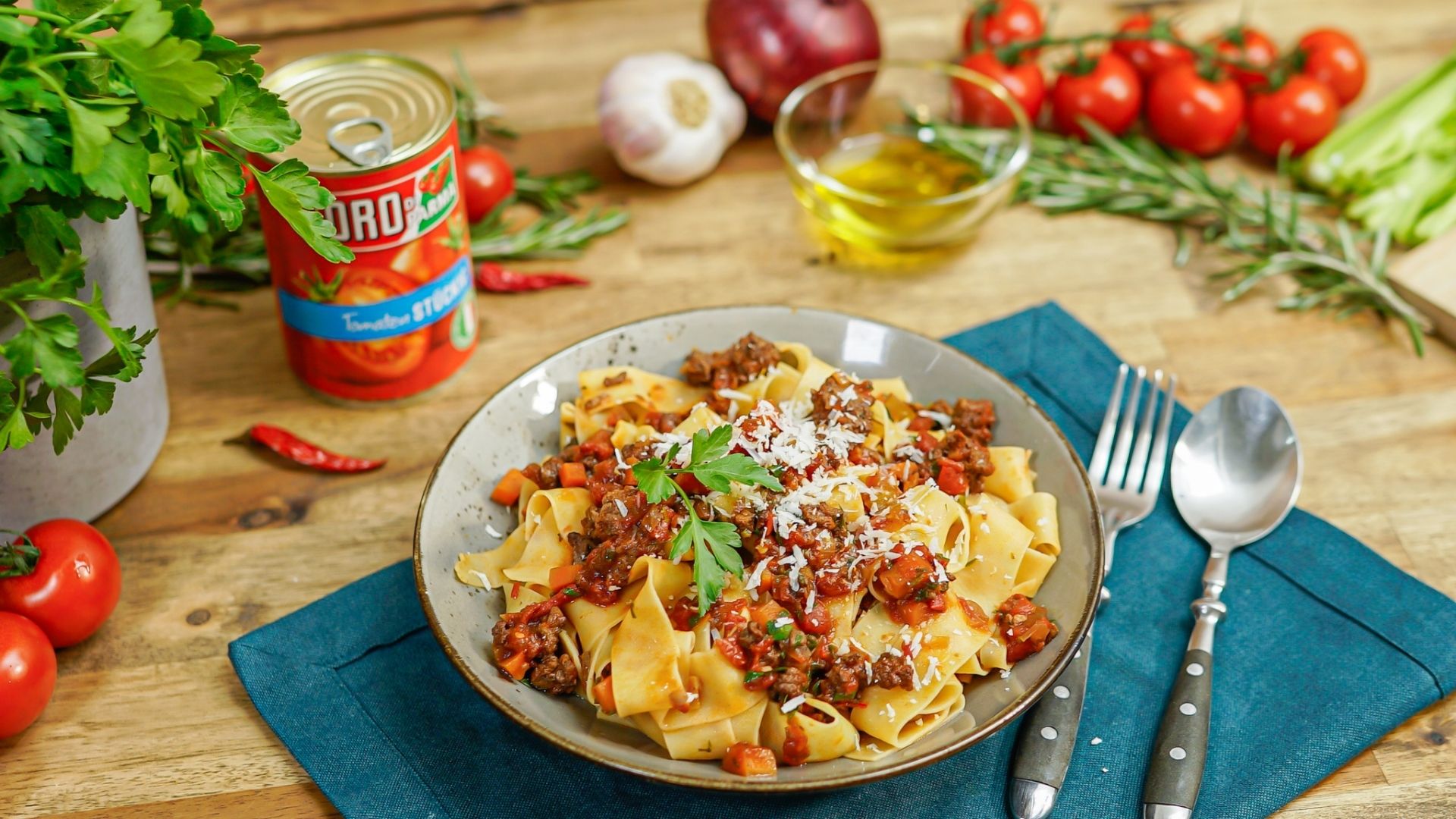 In einer Suppenschüssel ist ein italienischer Linseneintopf. Im Hintergrund liegen Tomaten, ein Salz- und Pfefferstreuer und eine Flasche Essig.