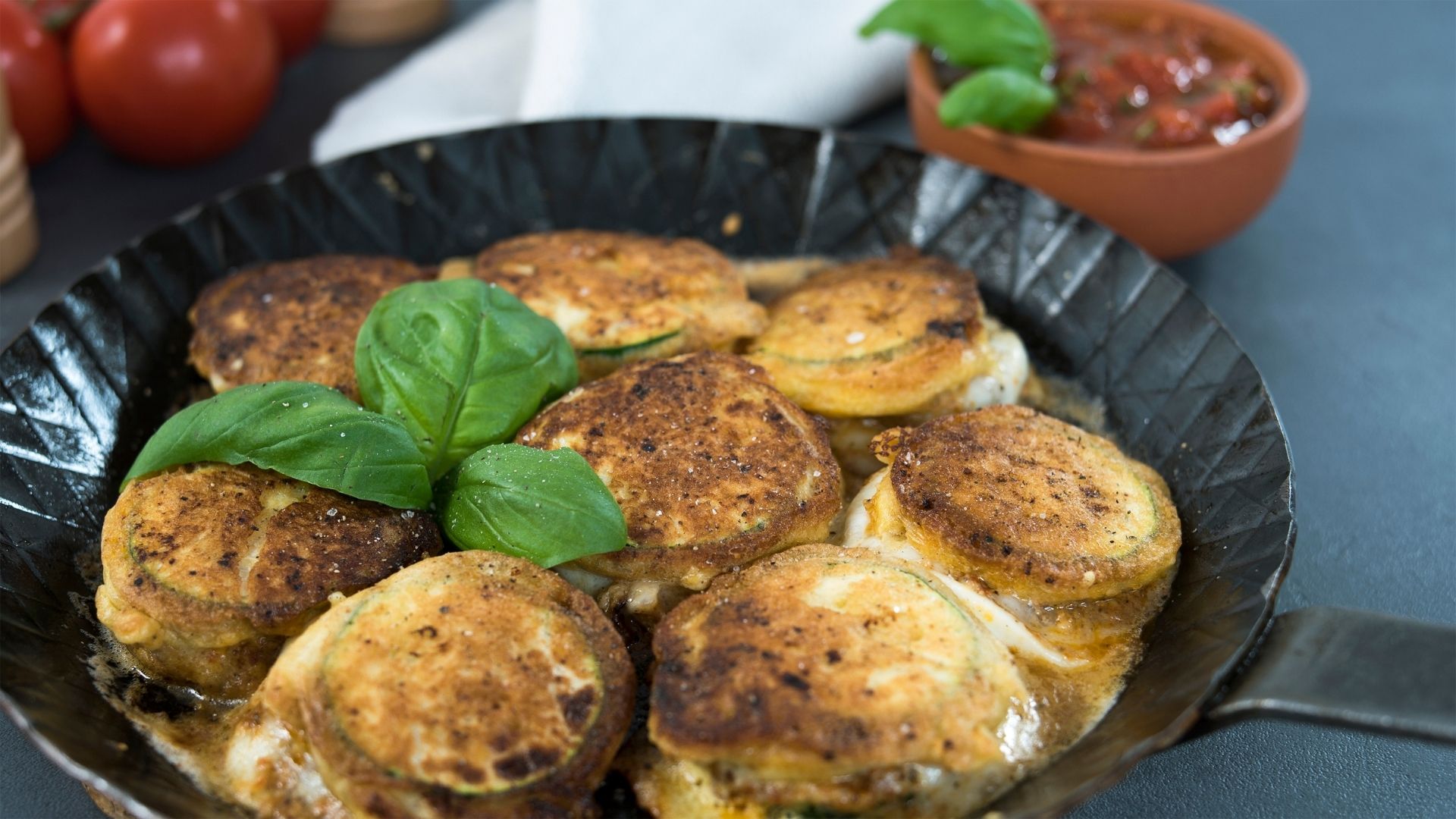 Überbackene Zucchini-Mozzarella-Scheiben in einer gusseisernen Pfanne