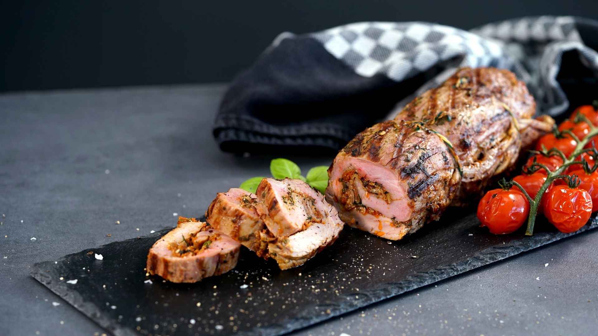 Eine Schiefer-Servierplatte mit gefülltem Schweinefilet in Scheiben geschnitten